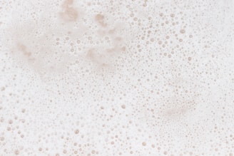 A layer of white foam with numerous small bubbles scattered throughout, giving a textured and frothy appearance.