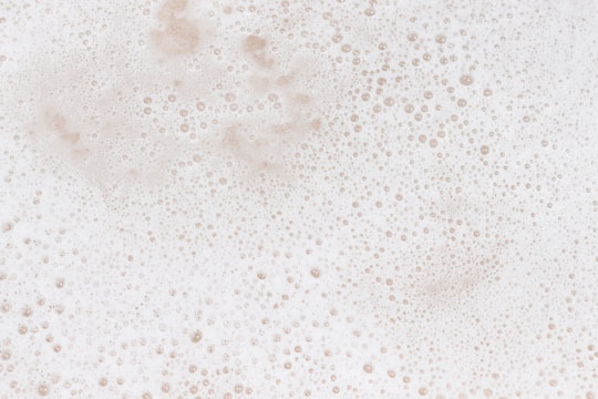 A layer of white foam with numerous small bubbles scattered throughout, giving a textured and frothy appearance.