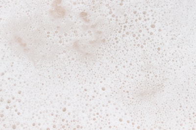 A layer of white foam with numerous small bubbles scattered throughout, giving a textured and frothy appearance.
