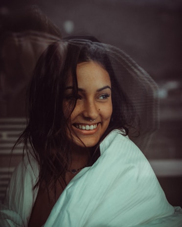 Close-up of a smiling person wrapped in a plush, comfortable pajama top, sitting by a window with morning light.