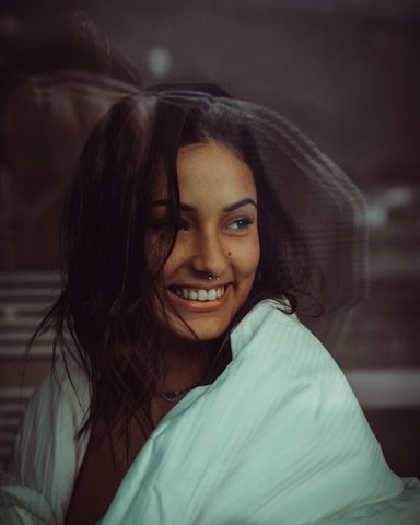 Portrait of Lismar smiling warmly in the elegant salon, surrounded by plants and soft neutral tones.