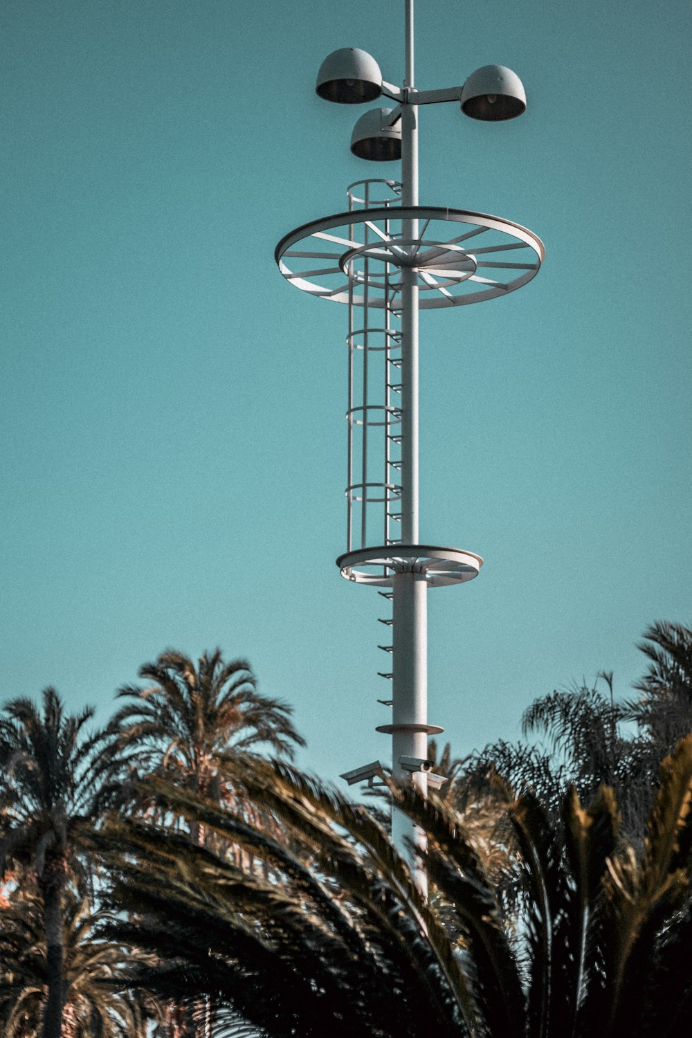 white metal tower beside palm trees