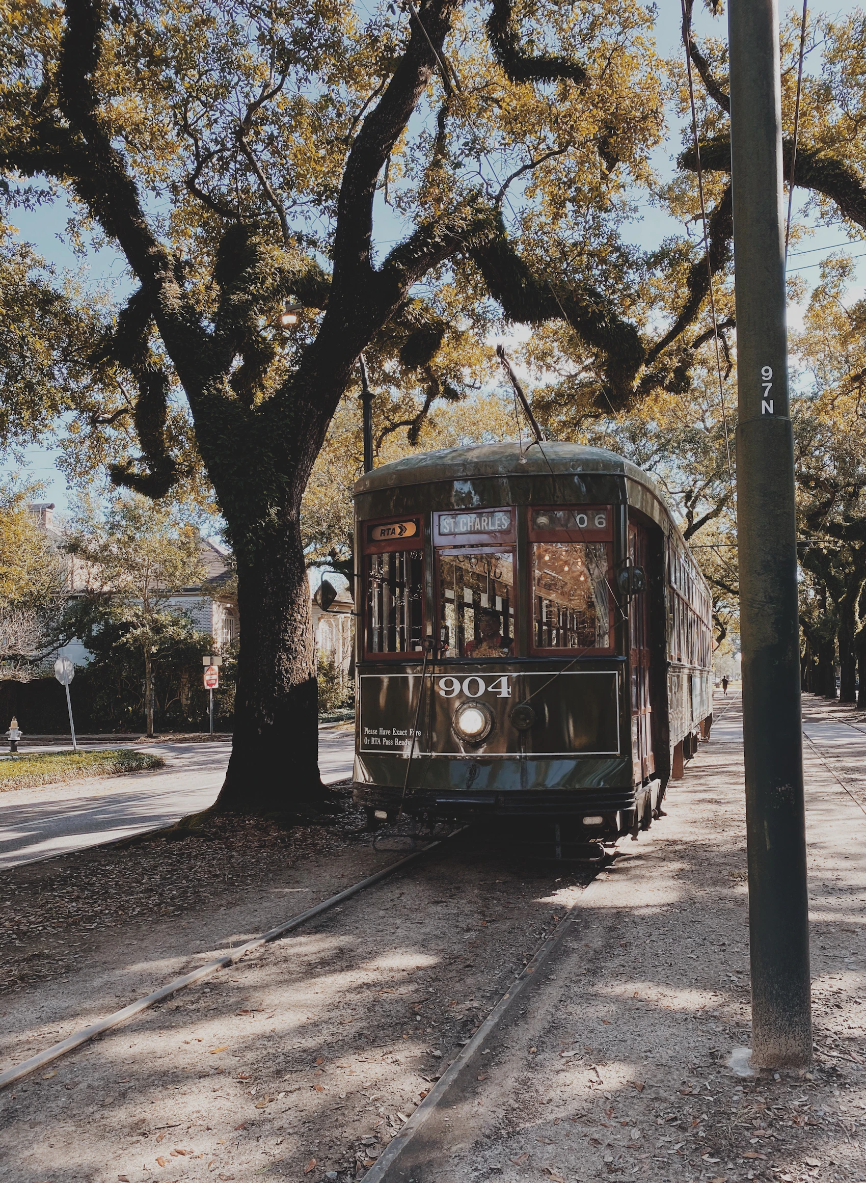 A historic green Saint Charles streetcar travelling through New Orleans