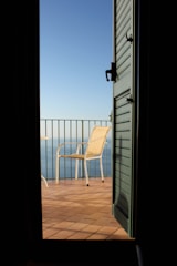 Balcony cabin door opening to a sea-facing deck with chairs.