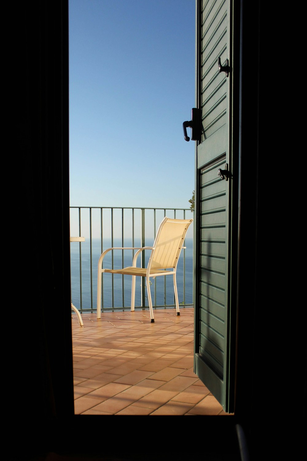 white metal armchair beside fence during daytime