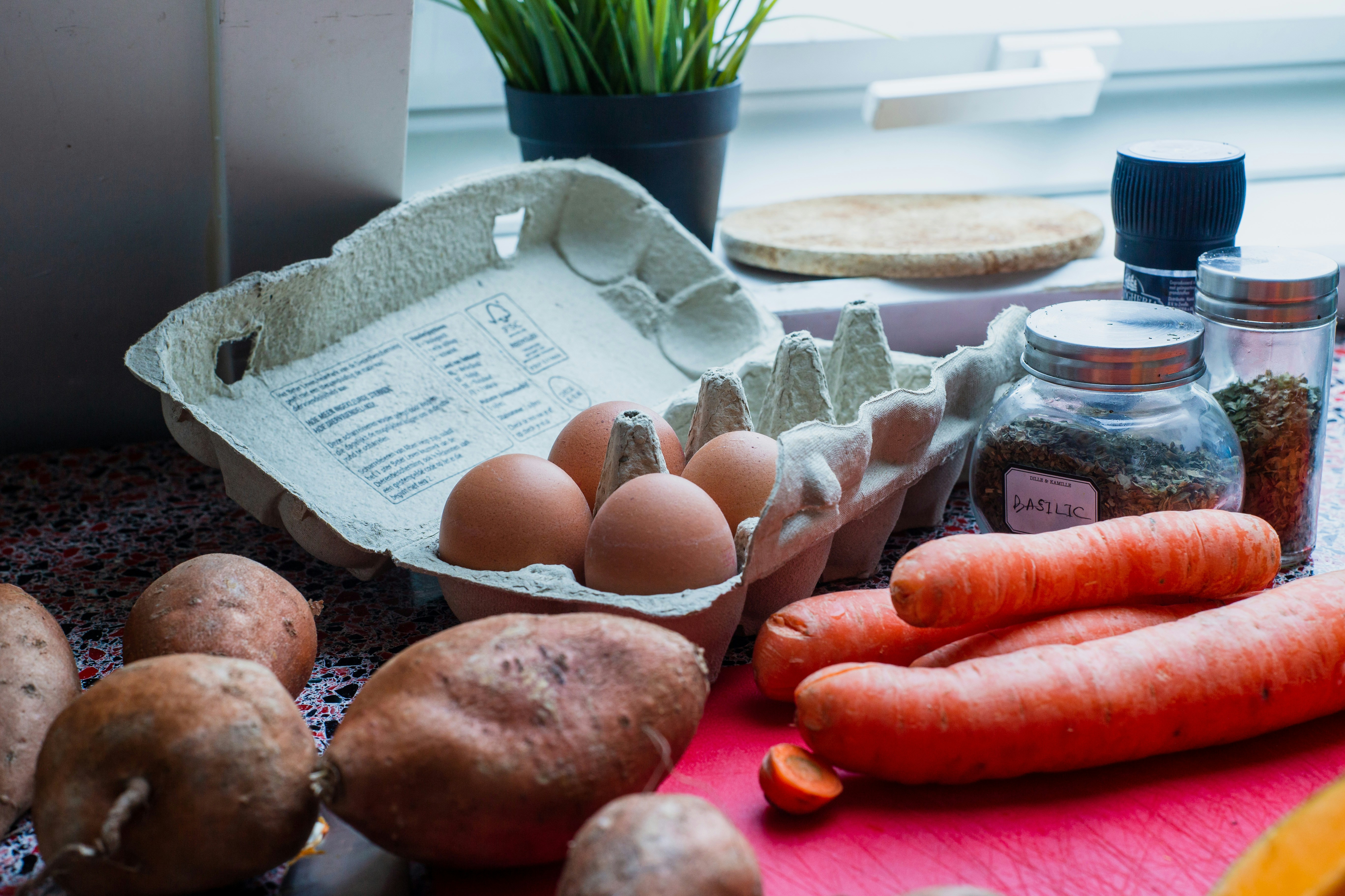 A family kitchen counter featuring a digital tablet with a meal planning app, surrounded by fresh greens, tomatoes, and a wooden cutting board.