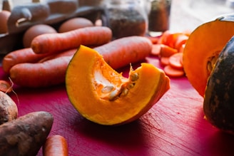Fresh carrots, spinach, broccoli, and pumpkin arranged on a wooden table.