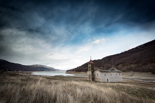 white concrete building near lake and mountain in Mavrovo North Macedonia