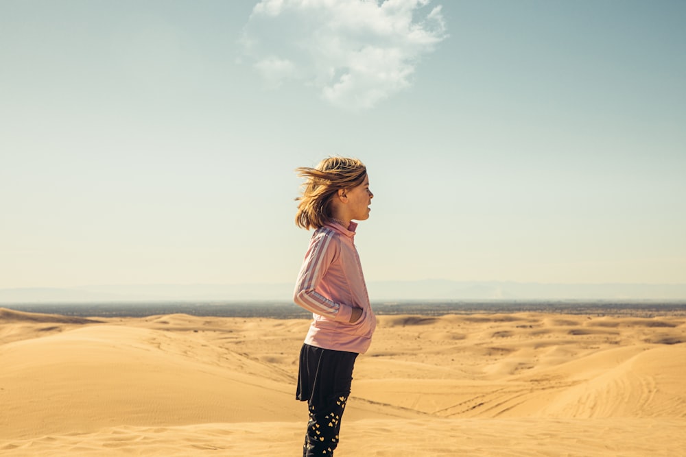 a woman standing in the middle of a desert
