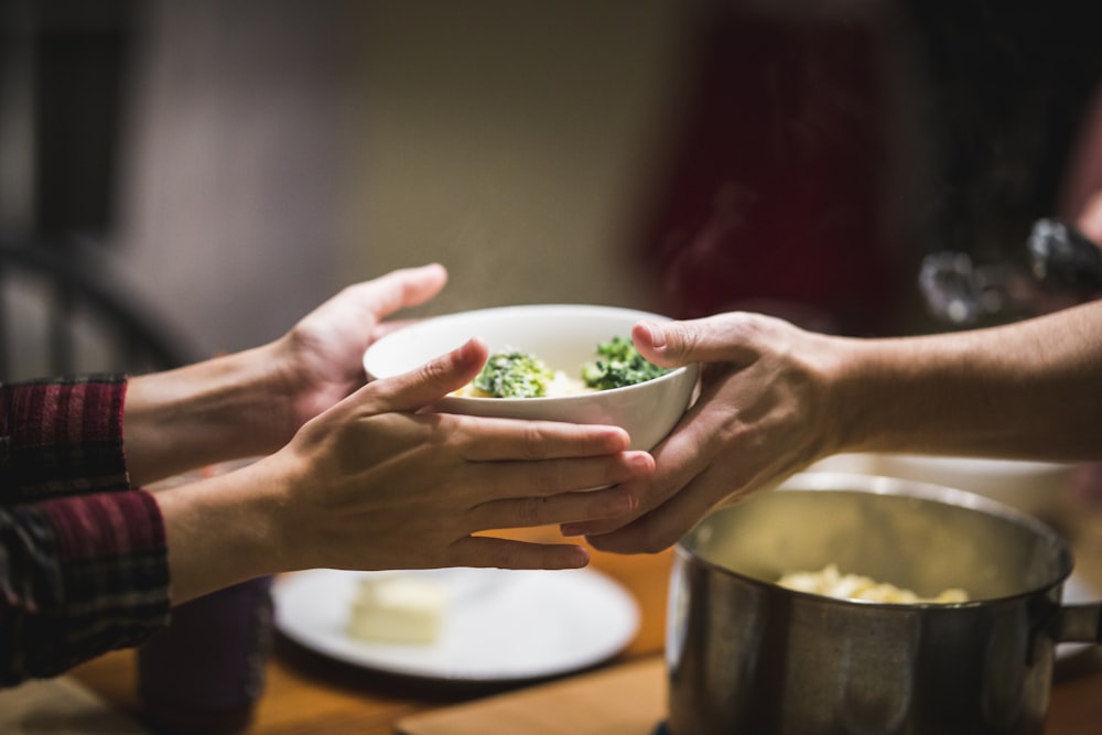 a couple of people holding a bowl of food