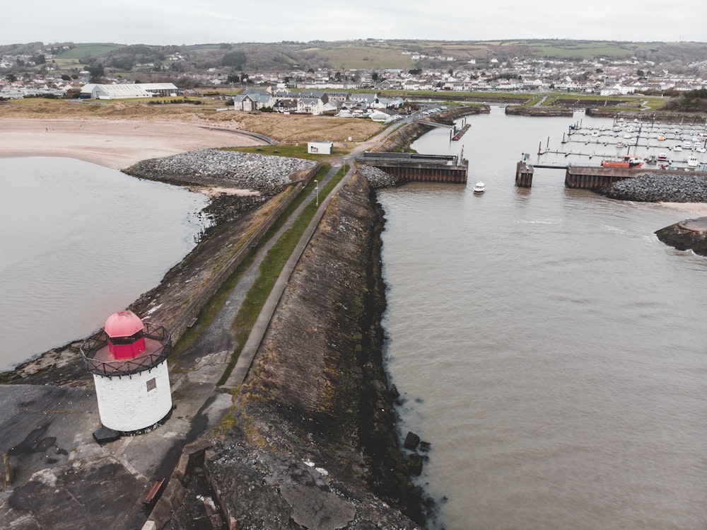 a red and white lighthouse sitting on the side of a river