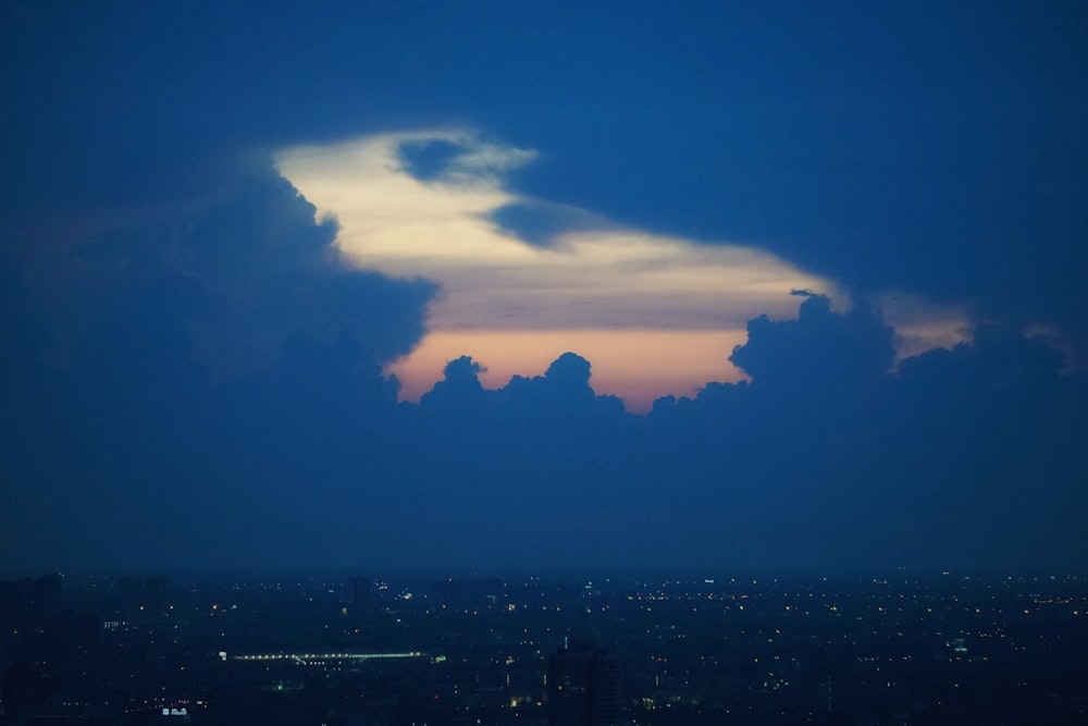 silhouette of city buildings under cloudy sky during night time