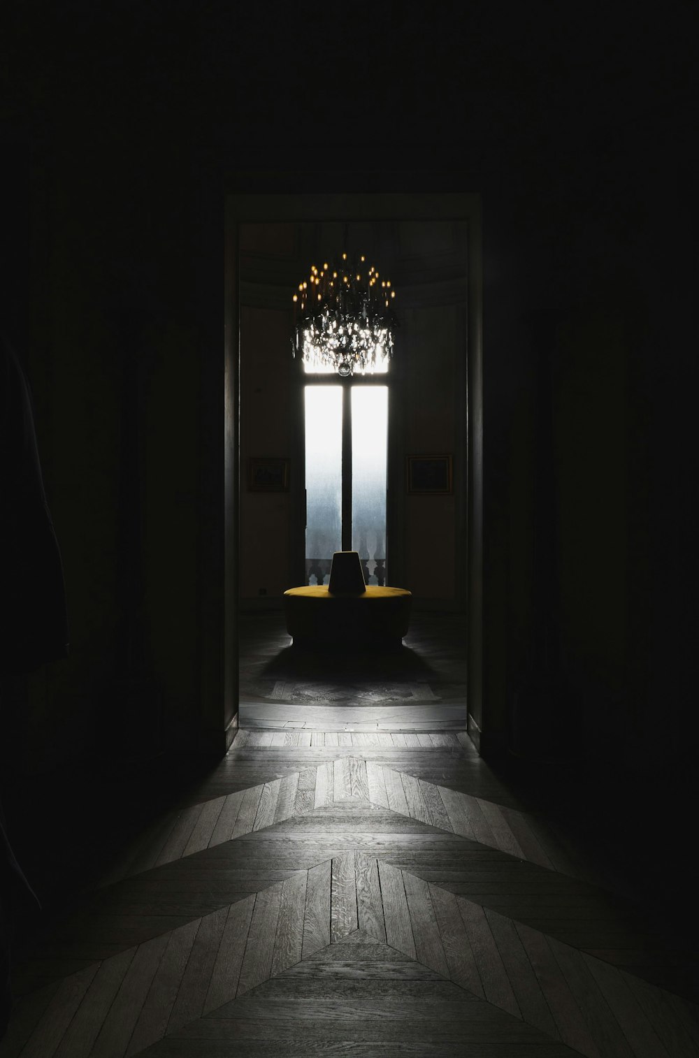 a dark hallway with a chandelier hanging from the ceiling