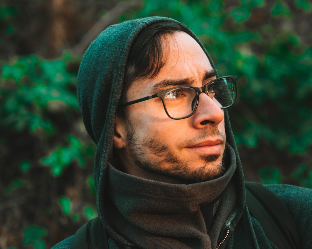 man in green hoodie wearing eyeglasses facing sideways