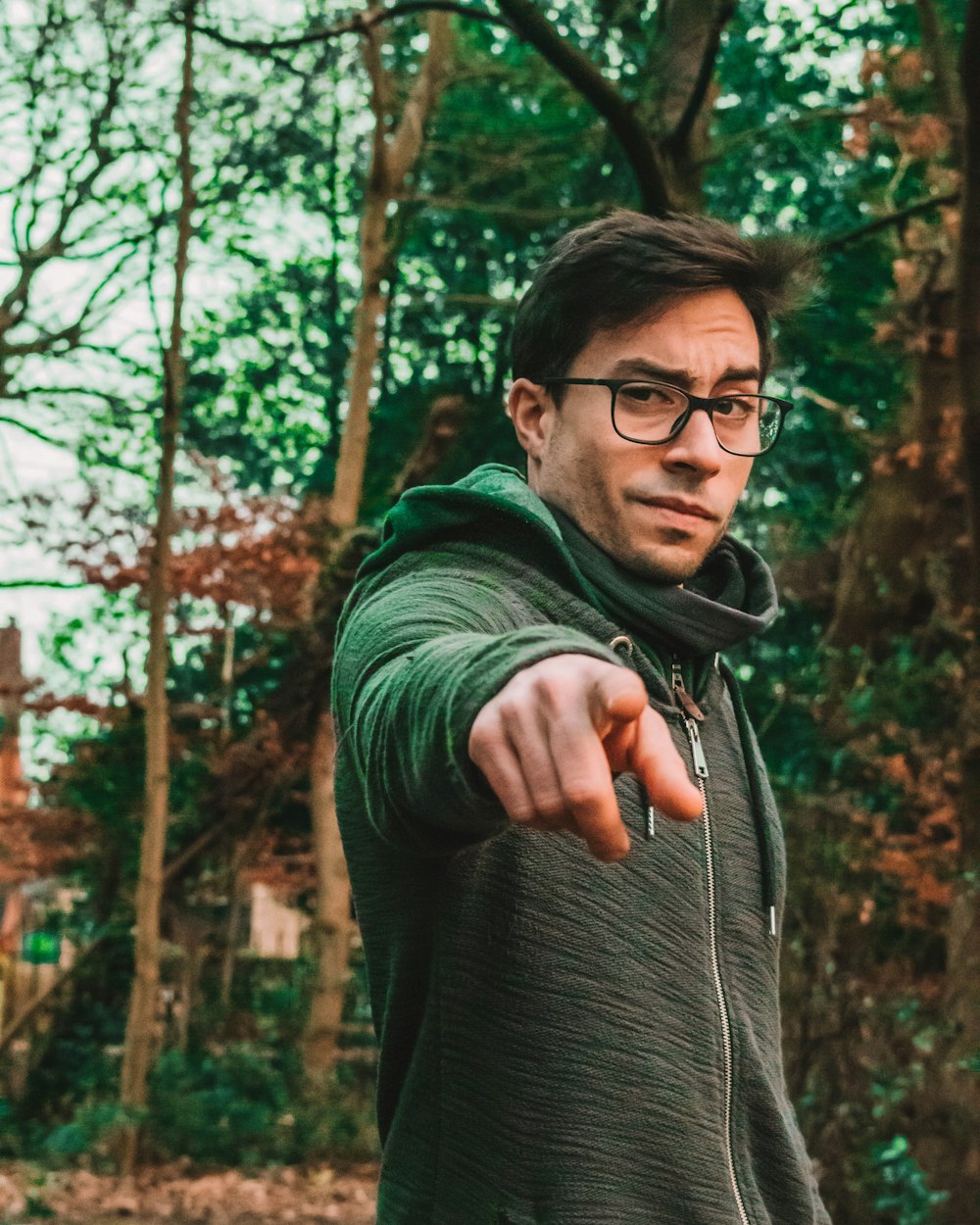 man in green and gray zip-up hoodie pointing his finger