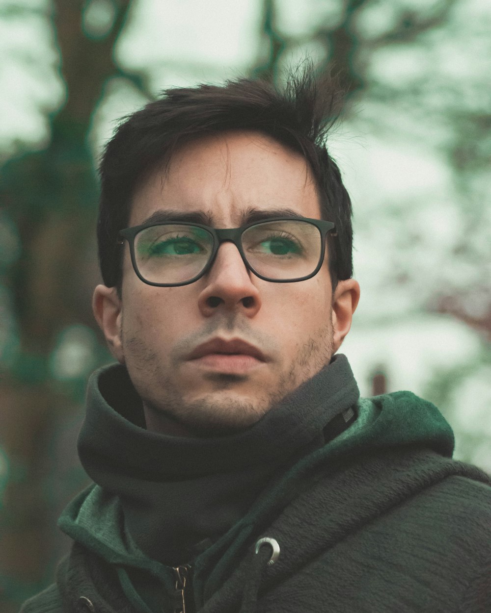 homme en sweat à capuche gris et vert portant des lunettes