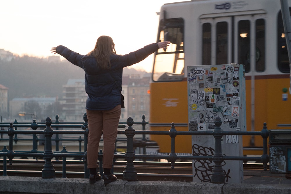 woman standing while raising hand in front of bus