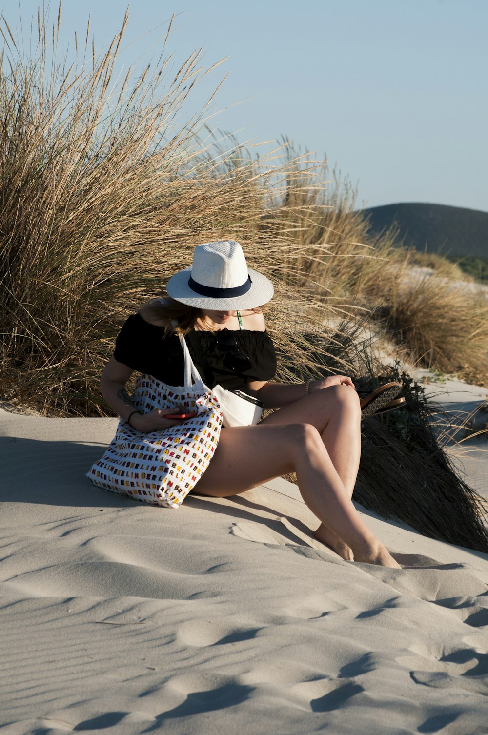 woman sitting on sand near grass