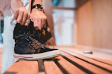 Woman sitting on a bench tying her comfortable, fashionable shoes.
