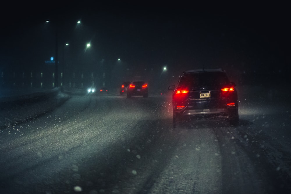 a couple of cars driving down a snow covered road