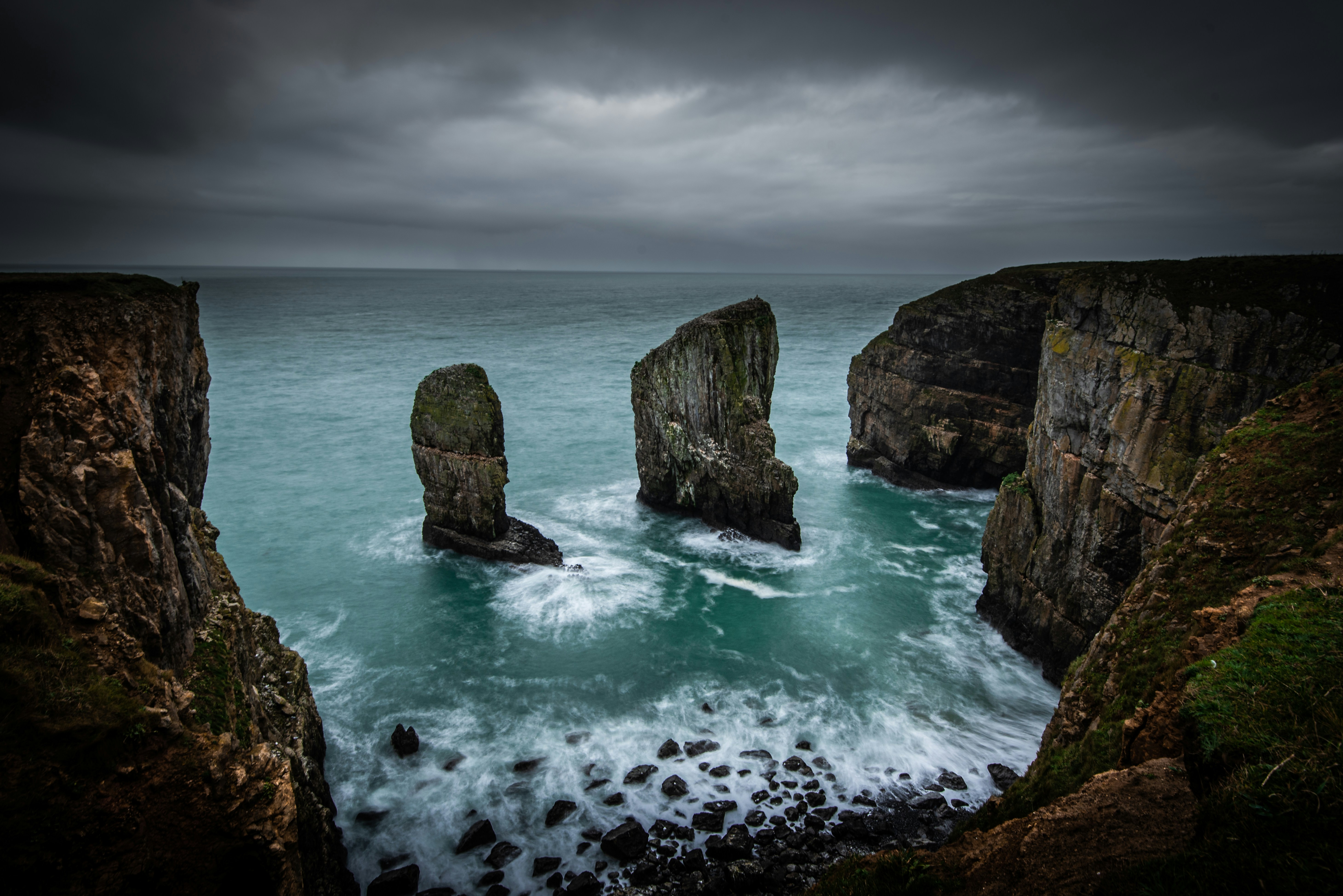 gray coastal rocks under cloudy sky during daytime, Photo taken of the Elegug sea stacks in Pembrokeshire on the Welsh coast. 
