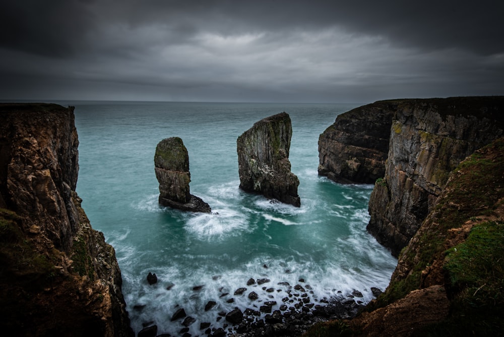 gray coastal rocks under cloudy sky during daytime