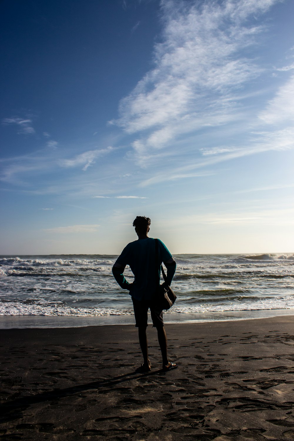 silhouette of person standing on seashore during daytime