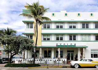 white and yellow coupe parking near white and green building under white and blue sky