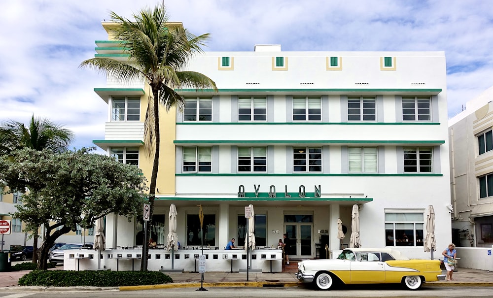 white and yellow coupe parking near white and green building under white and blue sky