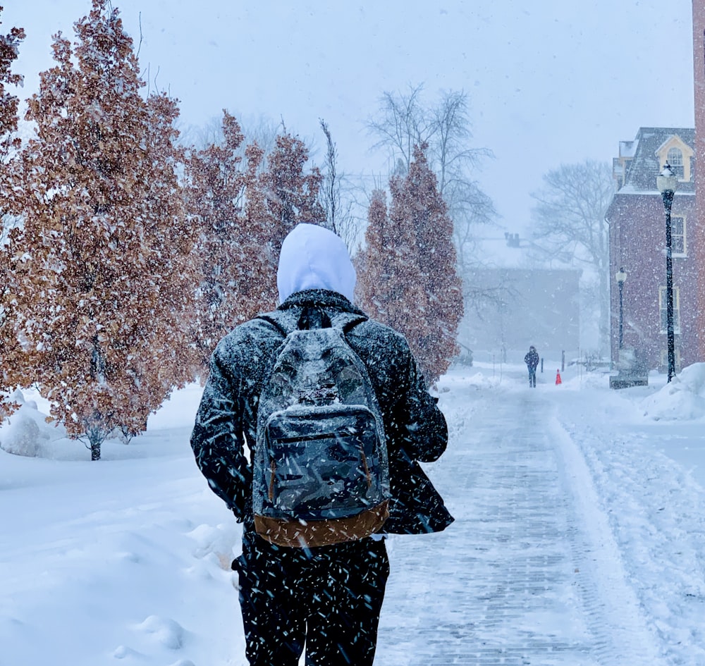 person walking during snowy weather at daytime