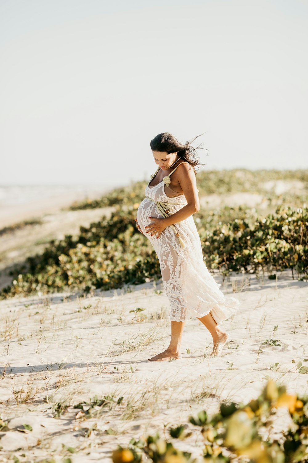 a woman in a white dress walking on a beach