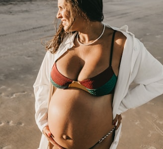pregnant woman in green-and-red bikini walking near outdoor during daytime
