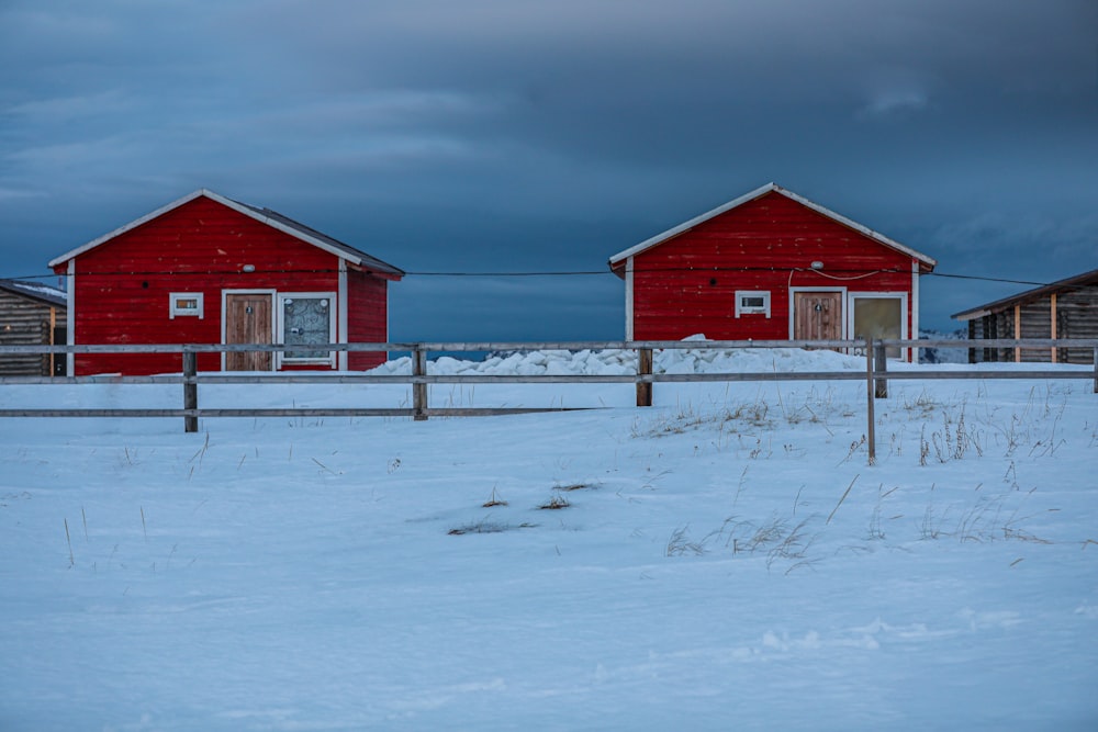 red wooden houses on snowy field under blue and gray sky