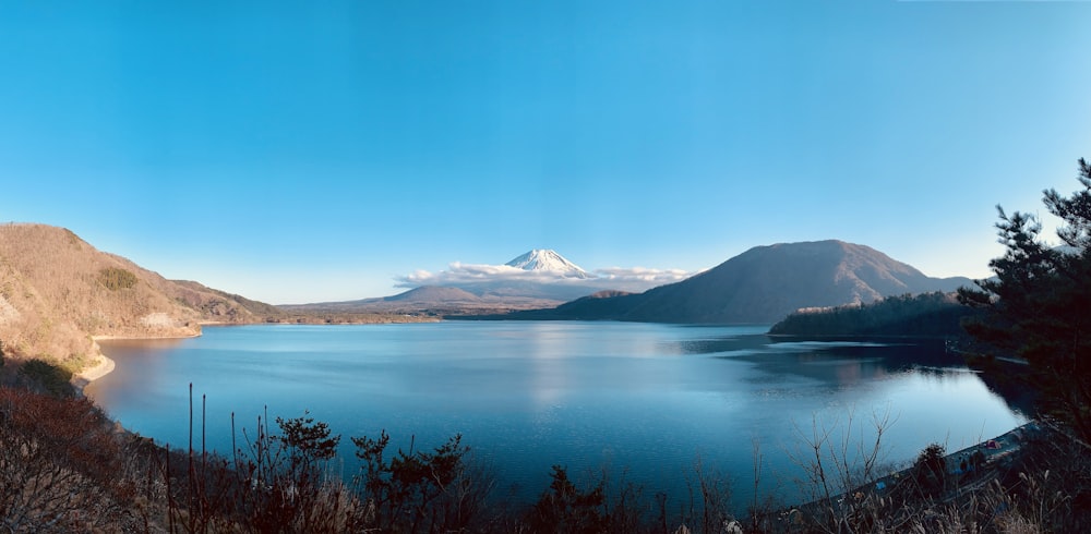 landscape photography of body of water viewing mountain under blue and white sky