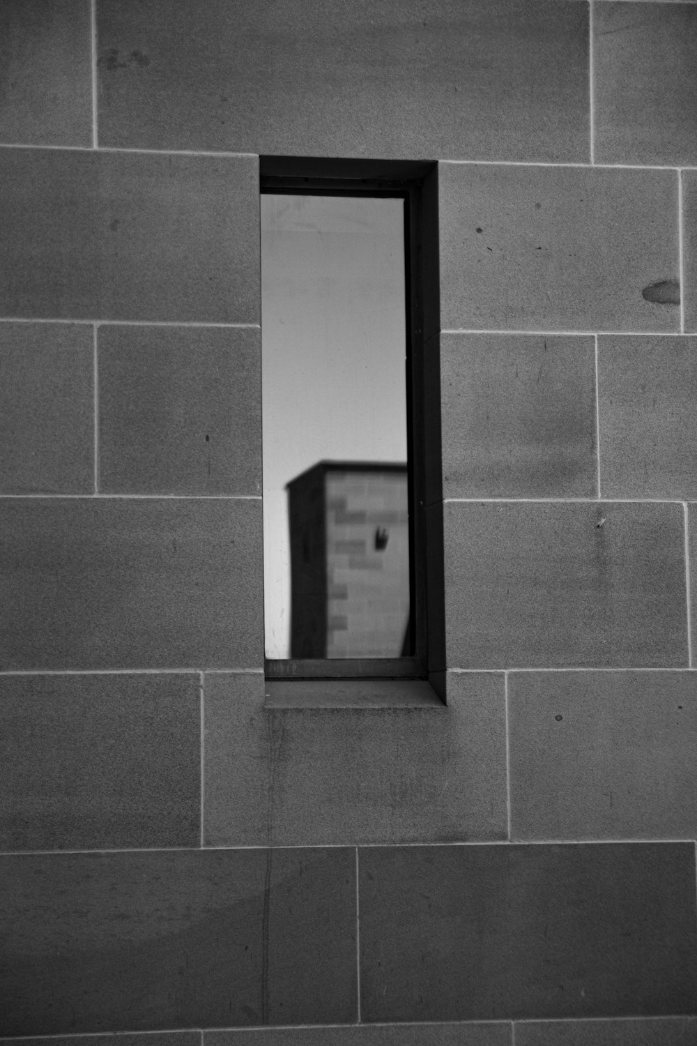 uma foto em preto e branco de uma janela em uma parede de tijolos