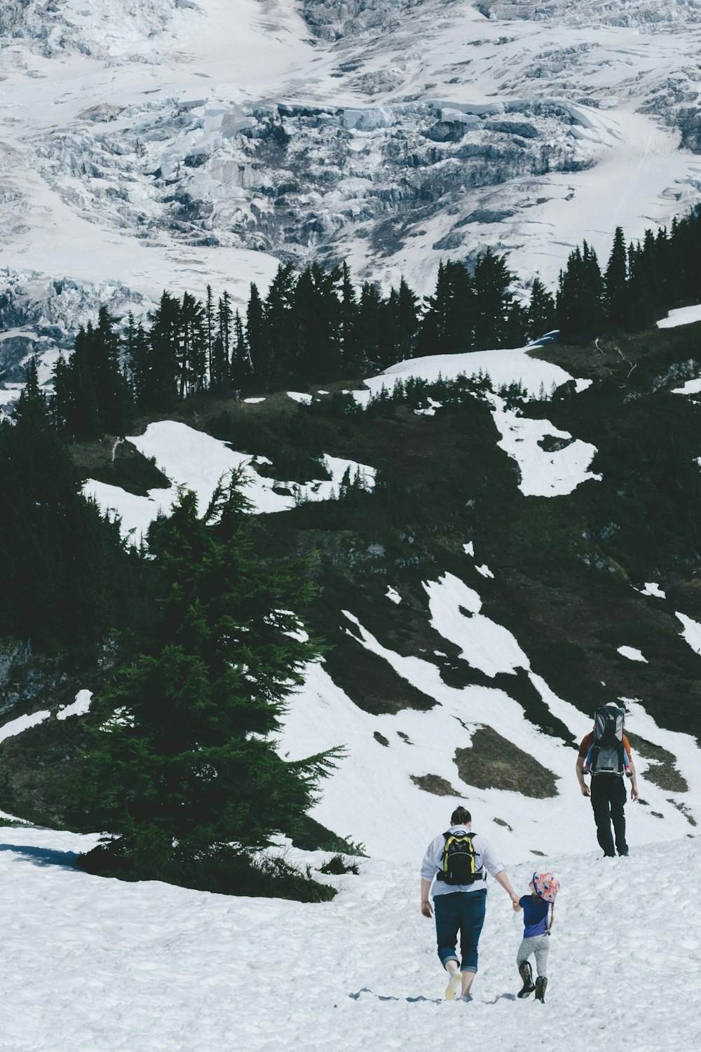 three people walking on snowy field during daytime