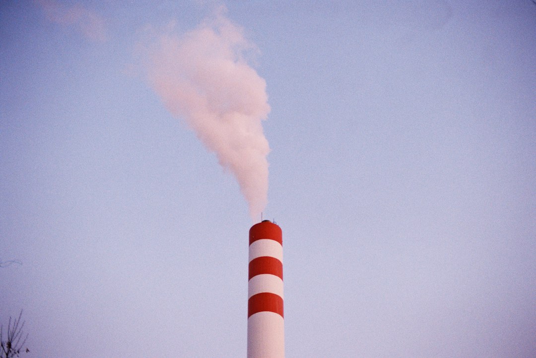 white smoke coming out from white and red factory,