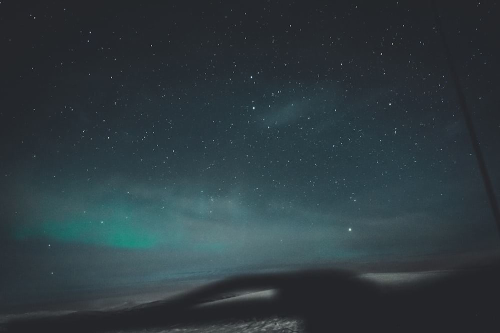 a night sky with stars and a green light