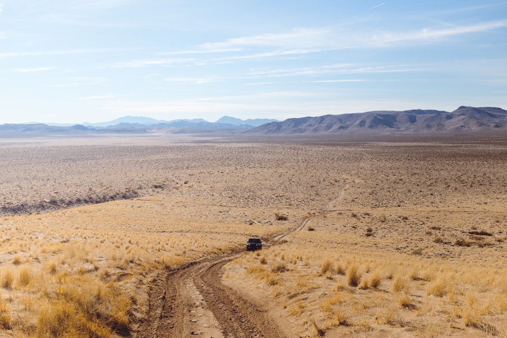 Fotografía de gran angular de un vehículo negro que viaja por el desierto durante el día