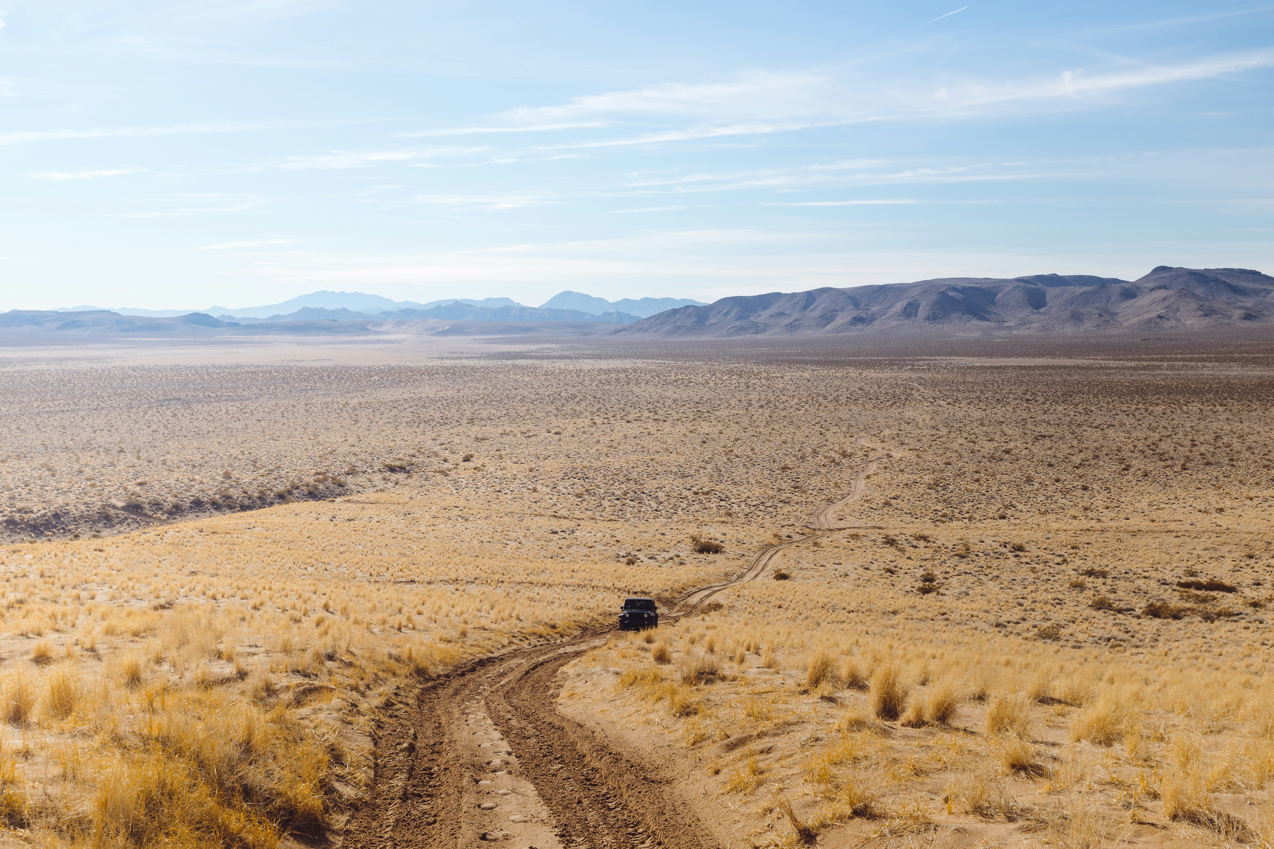 wide-angle photography of black vehicle traveling on desert during daytime