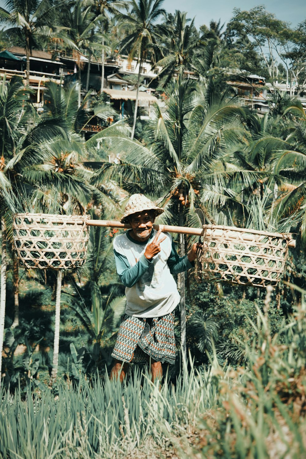 a man carrying a bamboo stick through a jungle