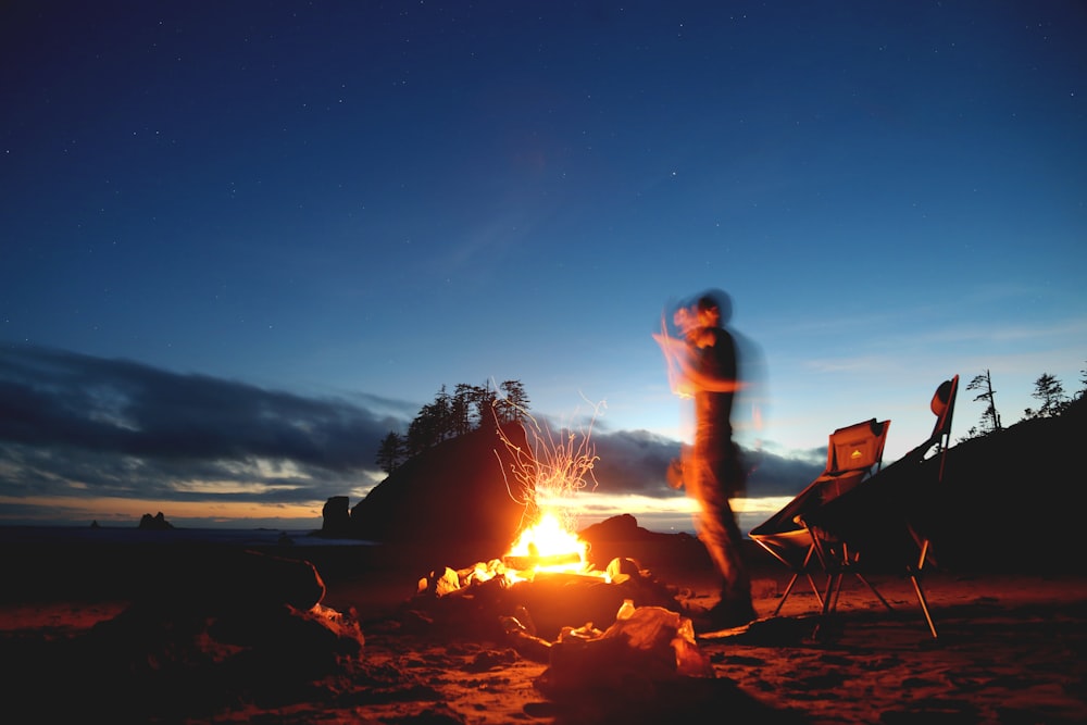 a man standing in front of a campfire at night