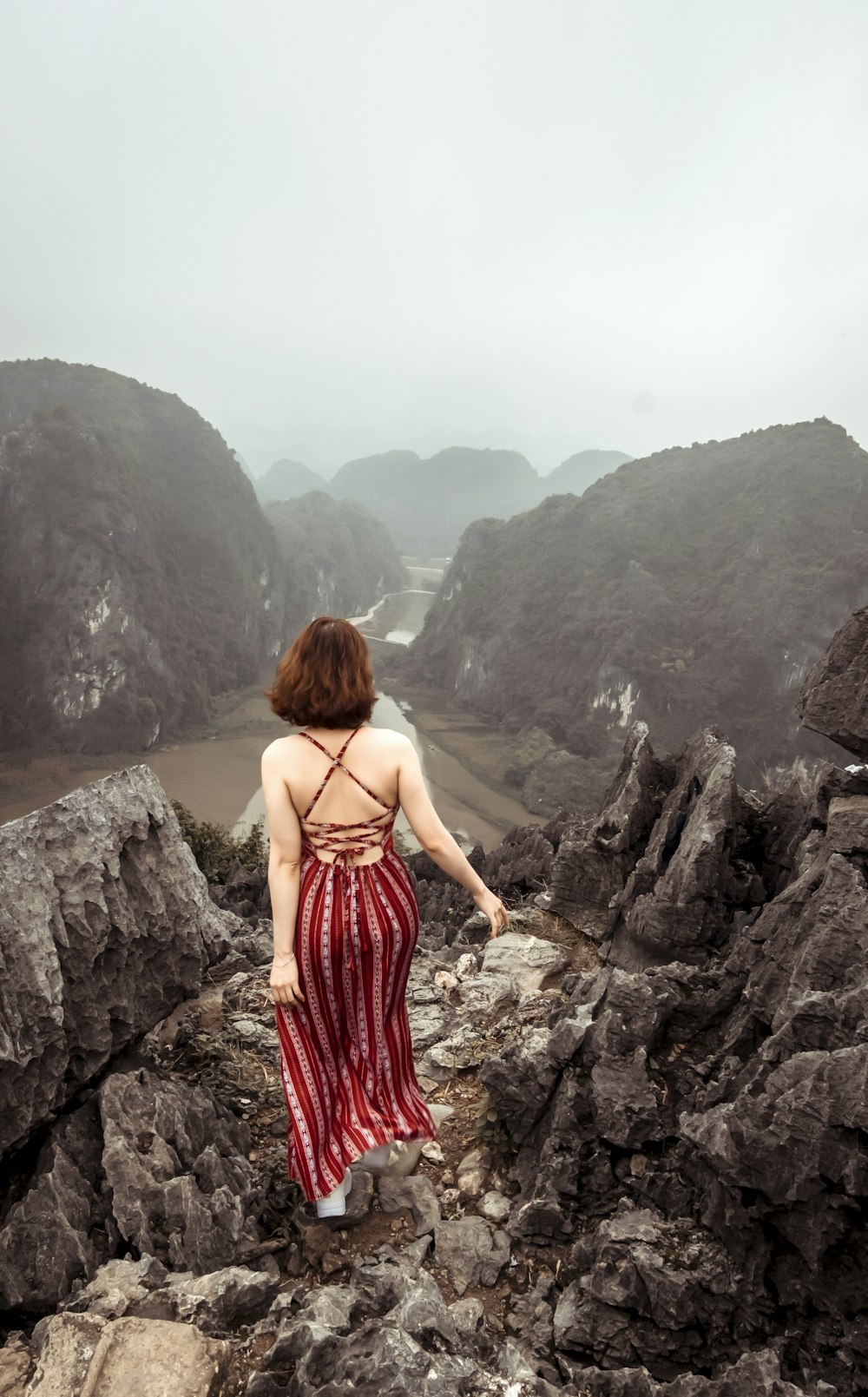 woman wearing red stripe dress standing on the mountain cliff