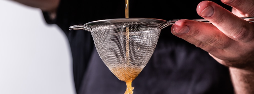 person holding strainer while pouring juice