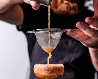 person holding strainer while pouring juice