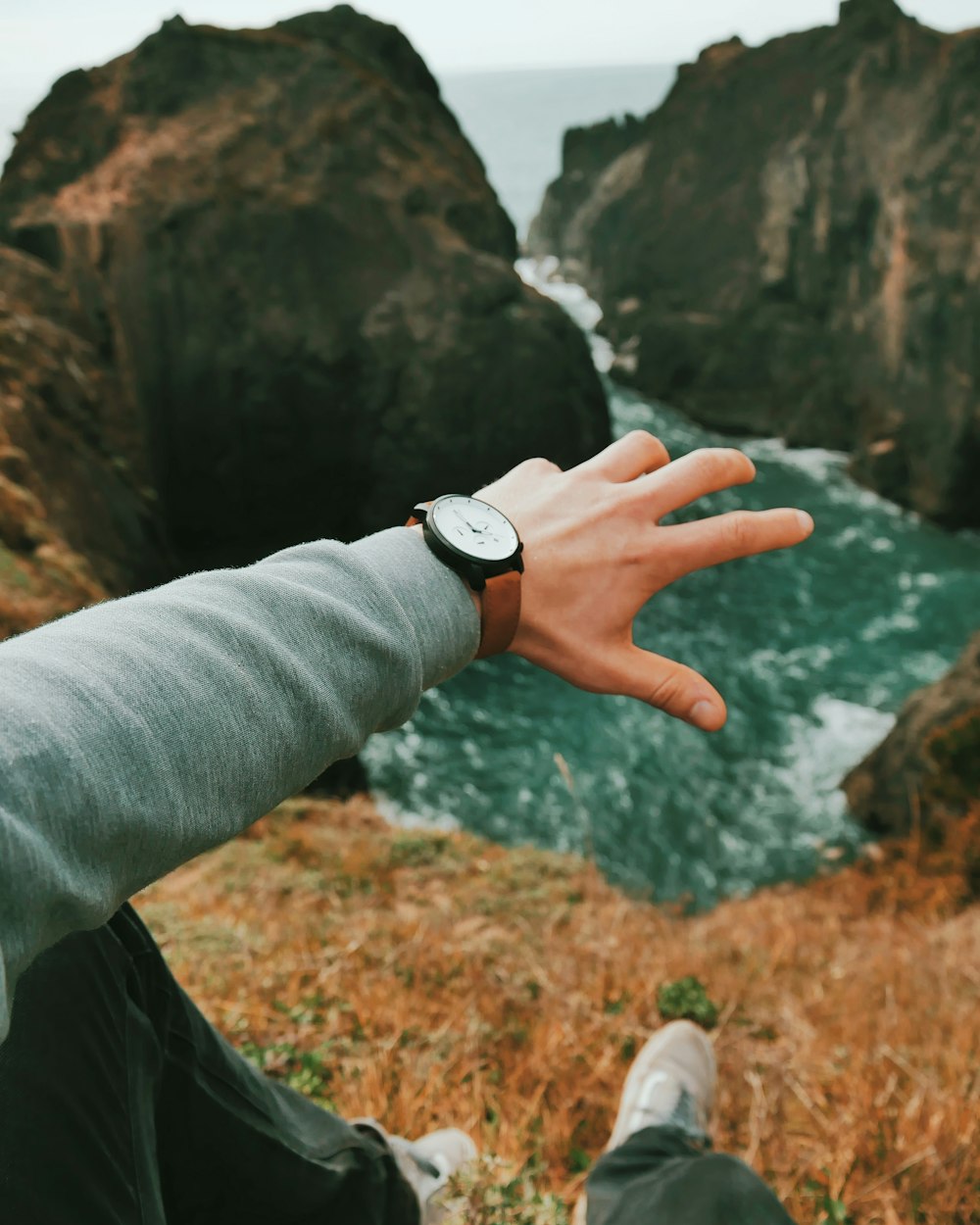 person wearing round silver-colored chronograph watch with leather band