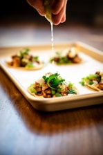 person squeezing fruit on food on tray