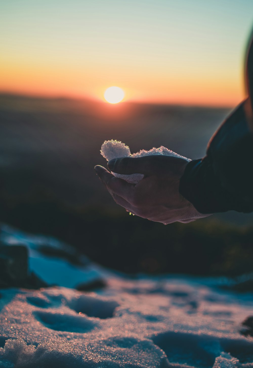 eine Person, die etwas in der Hand hält, mit einem Sonnenuntergang im Hintergrund