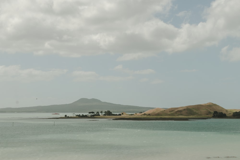 landscape photography of body of water viewing mountain under white and blue sky