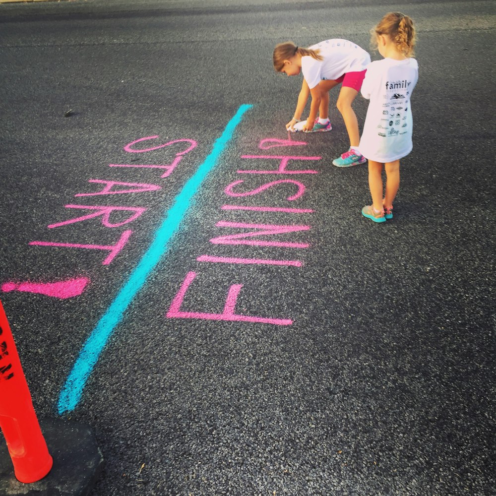 girl writing on the ground using a spray an